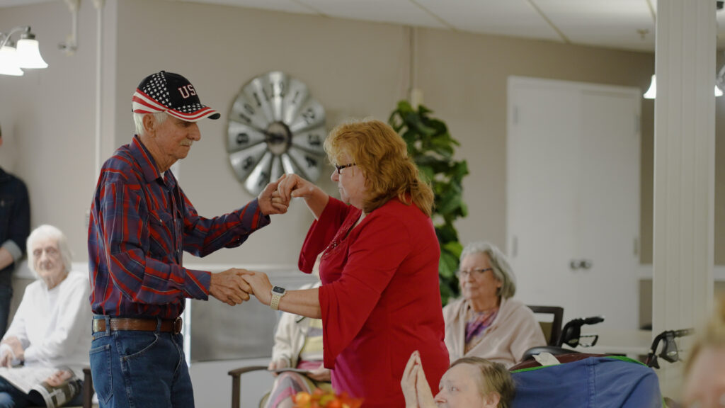 A man and a woman dancing together at a nursing home