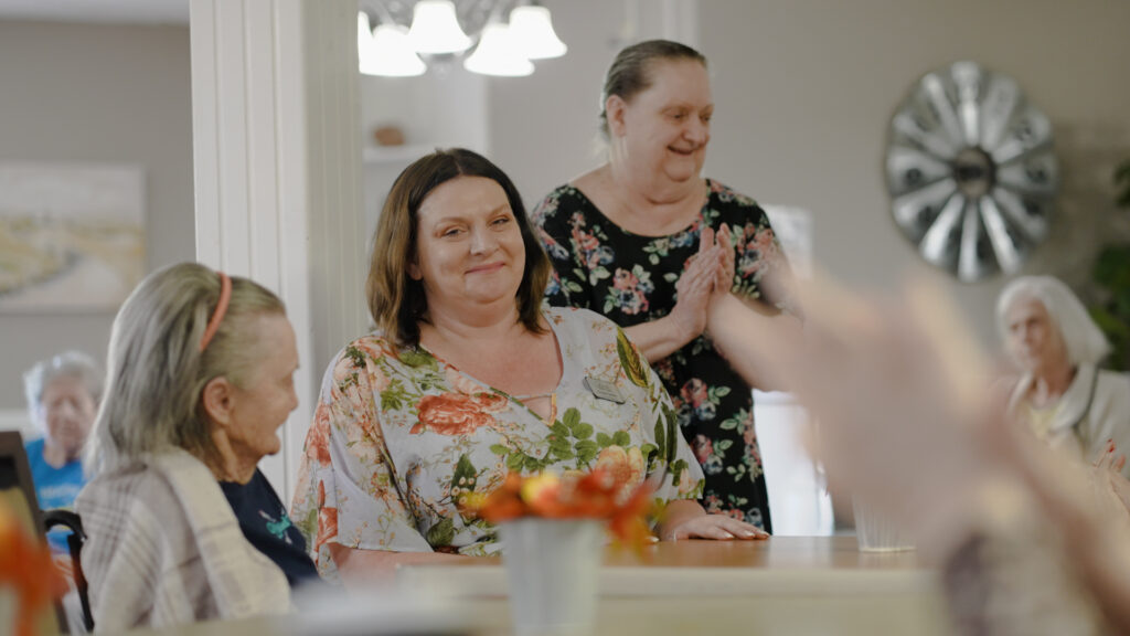 A group of women at a nursing home singing and smiling