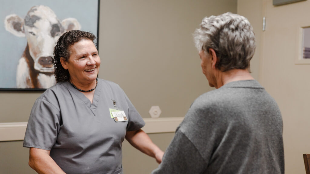A nurse speaking with a resident at Beebe Retirement, a skilled nursing facility and smiling