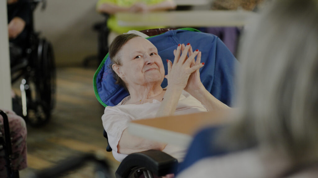 A woman who is part of Beebe Retirement's long term care service, clapping and smiling during an activity