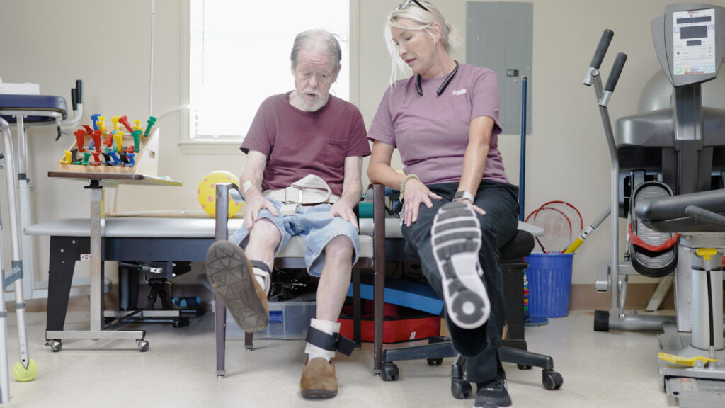A man and a nurse in physical therapy at a skilled nursing facility